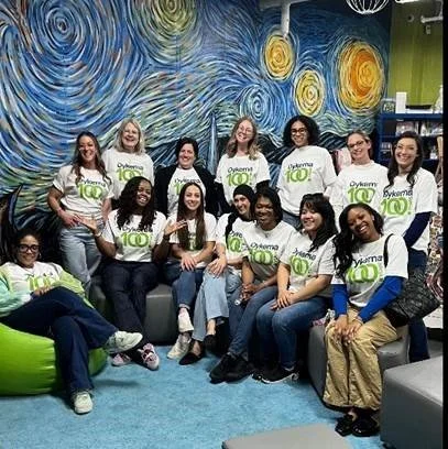 Group of women and girls wearing Oklahoma state T-shirts, gathered in a room with Vincent van Gogh's 'Starry Night' mural on the wall.