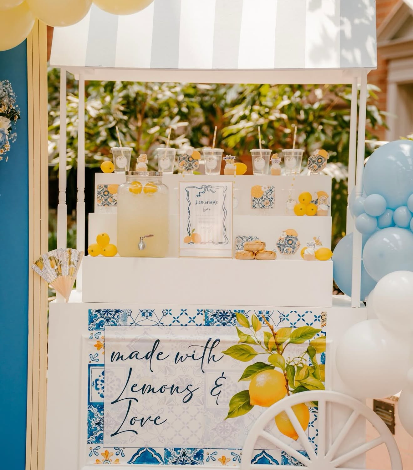 A lemonade stand decorated with lemons, yellow and blue accents, and a sign that reads "made with Lemons & Love."