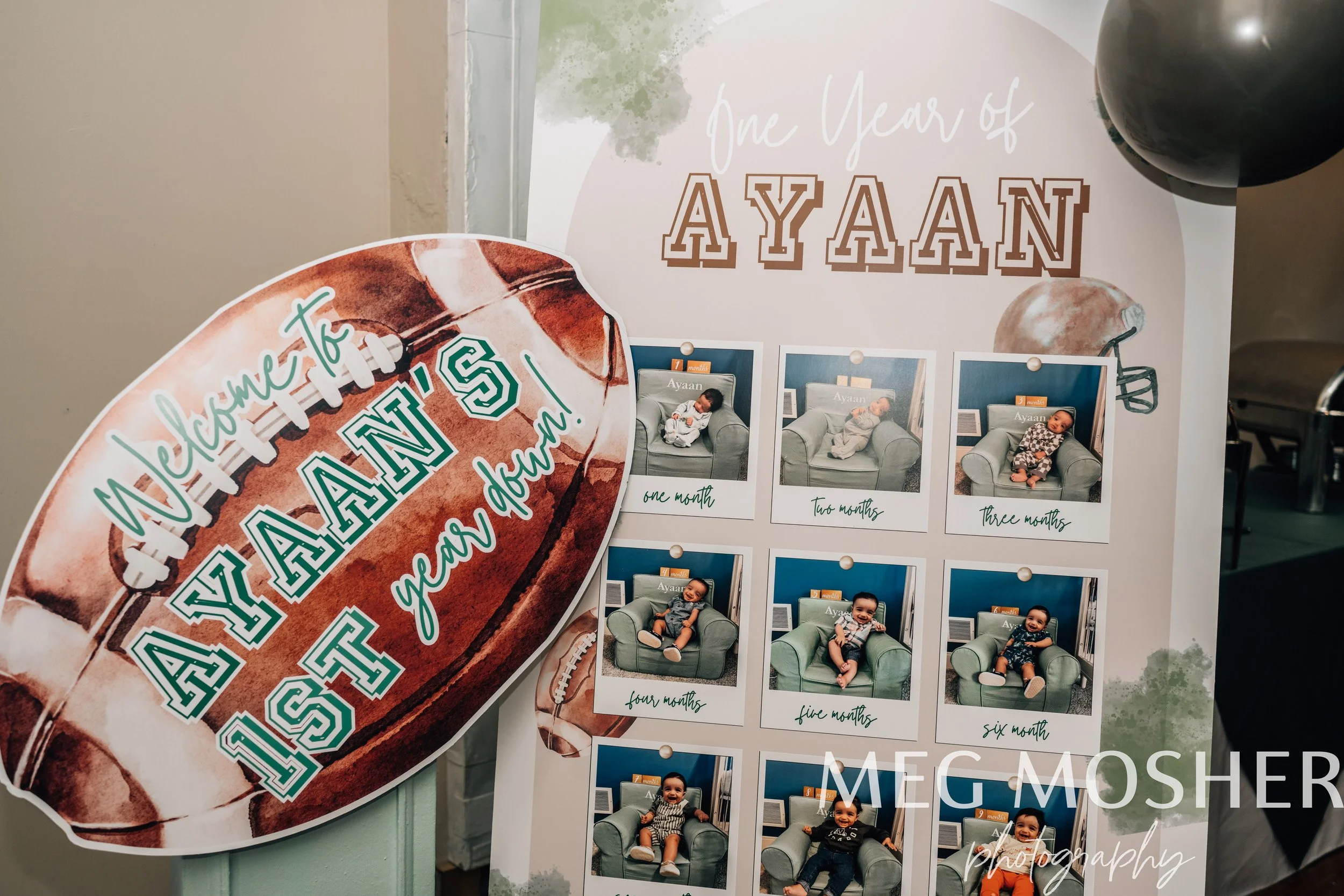 A display with a banner reading 'One Year of AYAAN' and photos documenting the first six months of a baby's life, including images of the baby sitting on a couch at one, two, three, four, five, and six months old.