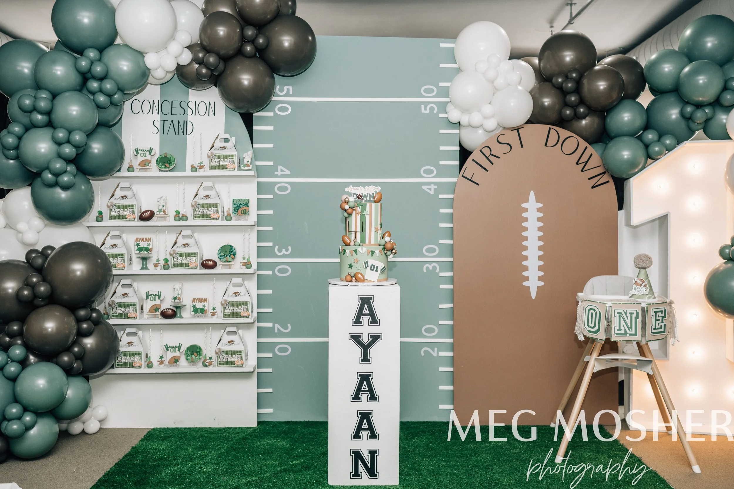 Decoration for a first birthday party with balloon arch, theme inspired by American football, featuring a cake and themed treats.