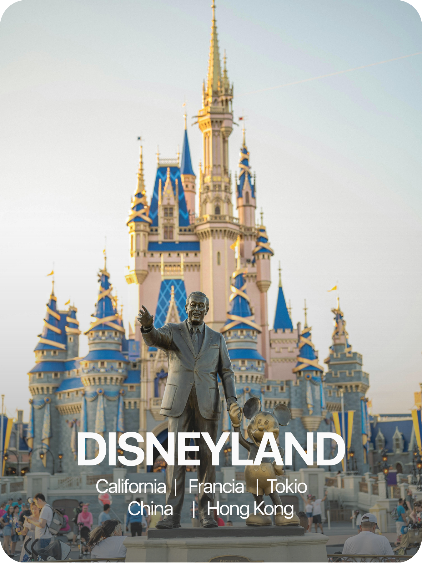 Estatua de Walt Disney y Mickey Mouse frente al castillo de Disneyland en California, con visitantes en el parque.