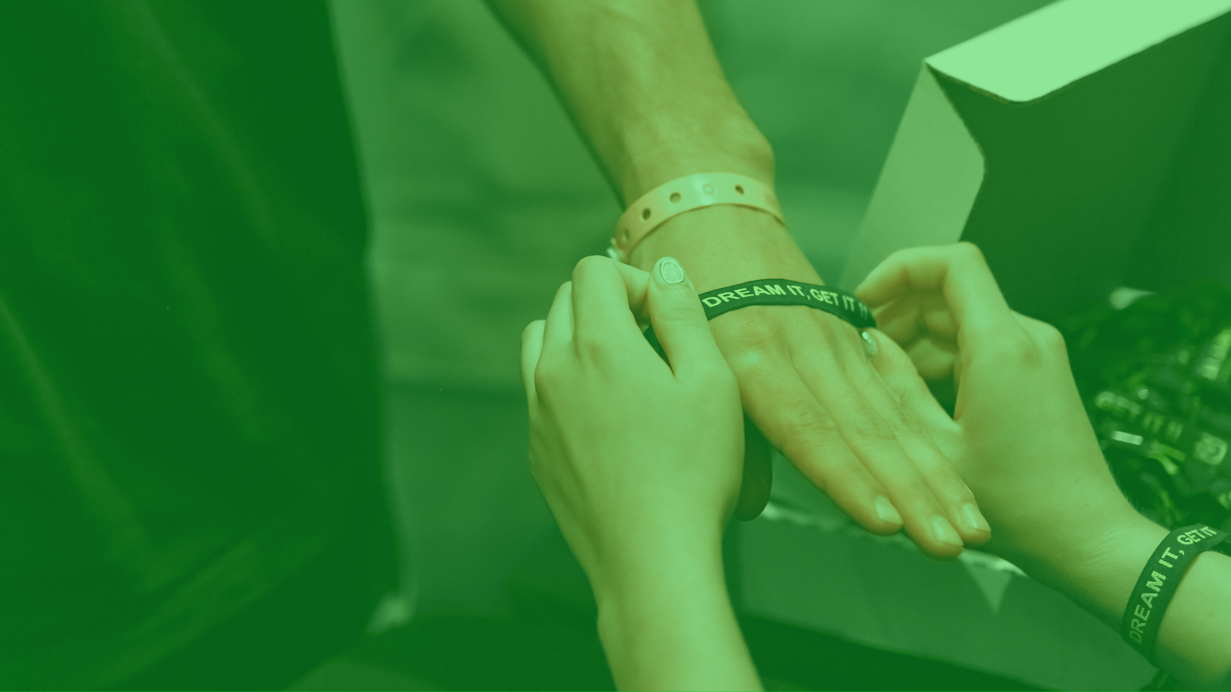 Mano de alguien poniéndose una pulsera con la frase 'DREAM IT, GET IT' en una muñeca.