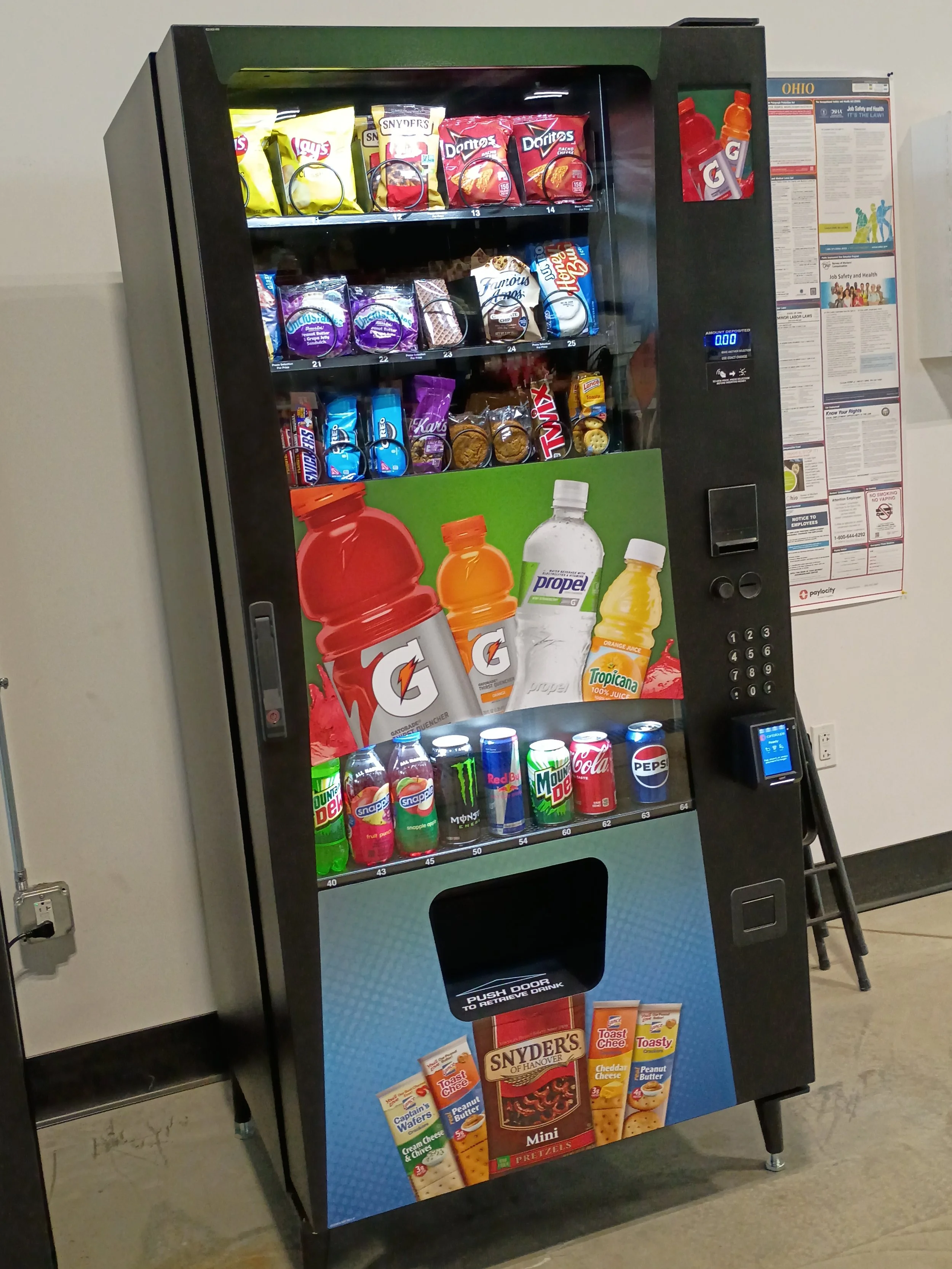 A vending machine stocked with snacks and beverages, including chips, candy, bottled water, canned soda, and energy drinks.