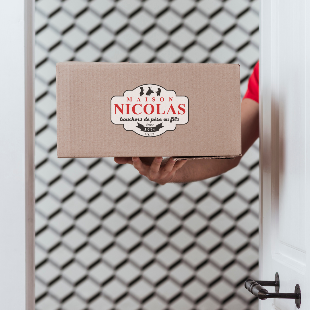 Une personne tenant une boîte en carton avec un logo de la maison Nicolas, spécialisée dans la charcuterie, sortant d'une porte.