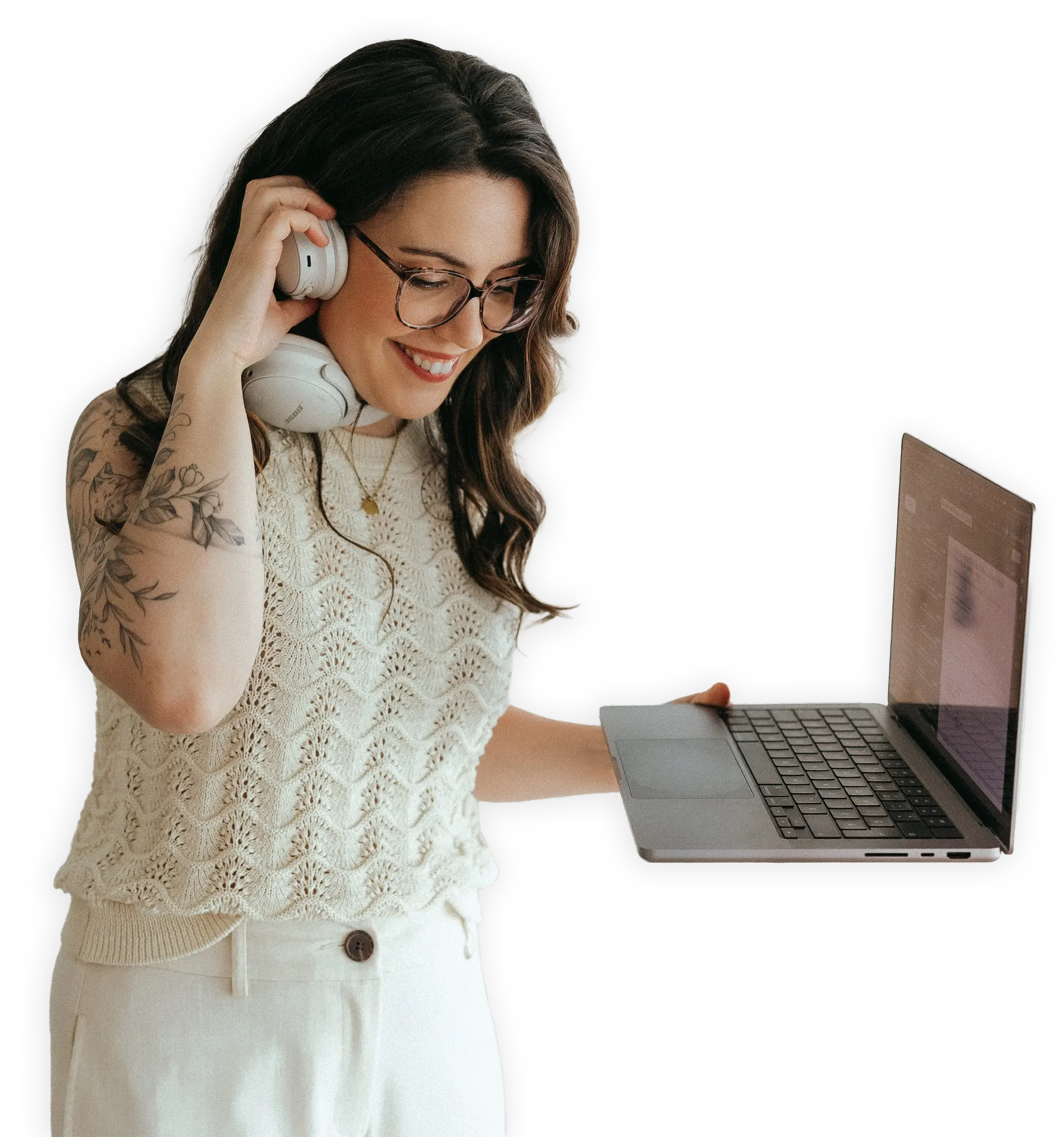 Une femme portant des lunettes, des vêtements beige, tient un ordinateur portable dans la main gauche et porte un casque audio blanc tout en souriant, avec un fond noir.
