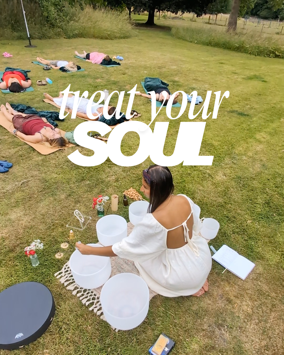 A group of people lying on the grass practicing yoga outdoors, while a woman in a white dress plays crystal singing bowls in front of them. The image includes text that says 'treat your soul.'
