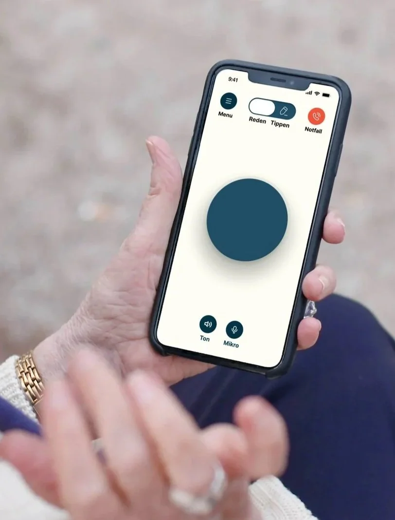 Eine Hand hält ein Smartphone mit der geöffneten Amara™ App. Auf dem Bildschirm ist eine Notfallfunktion für Alarm oder Notruf zu sehen, die im Ernstfall schnelle Unterstützung ermöglicht.