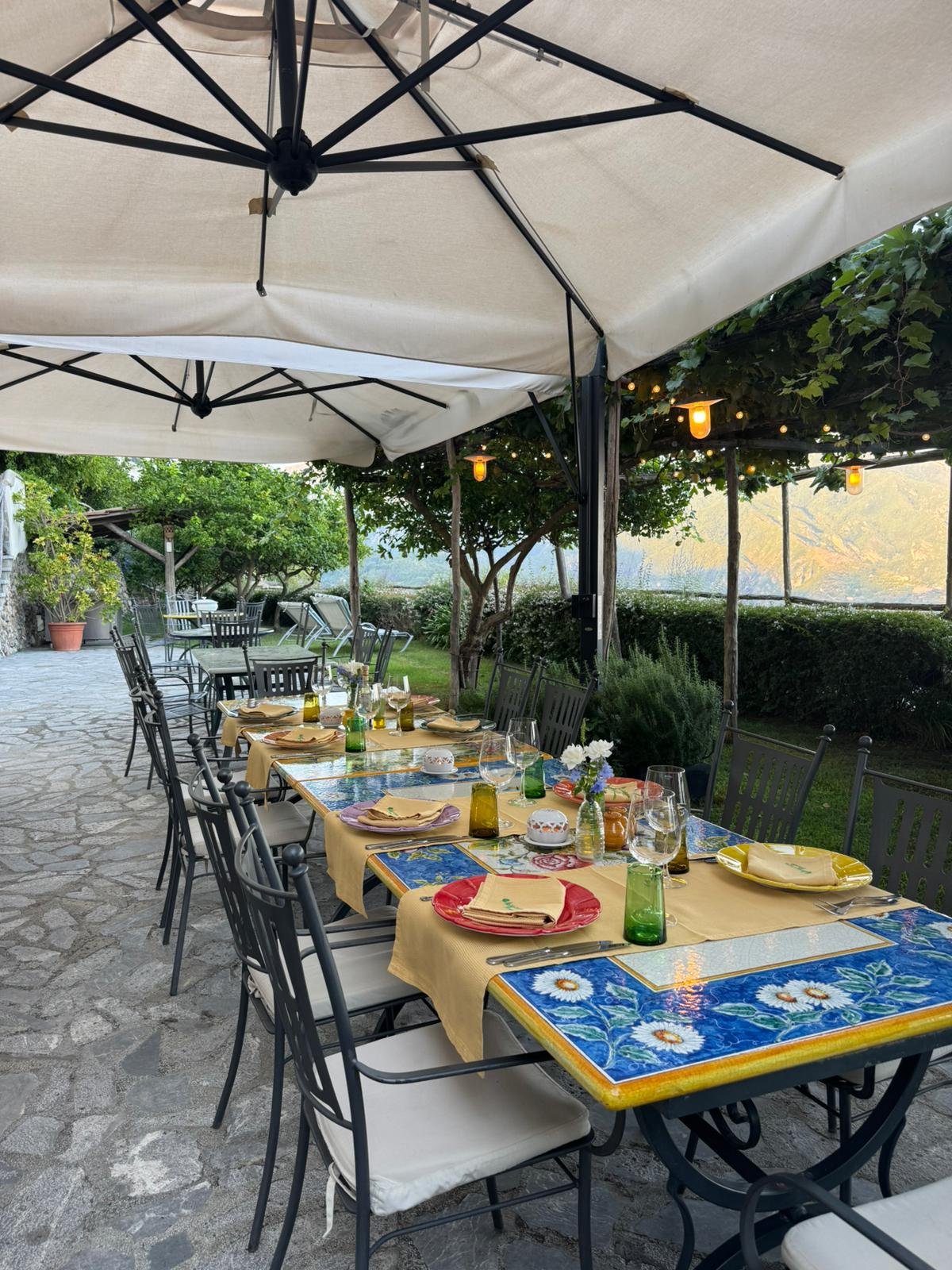 Decorative sign in Italian with four flower pots labeled with people's names and a quote about happiness.