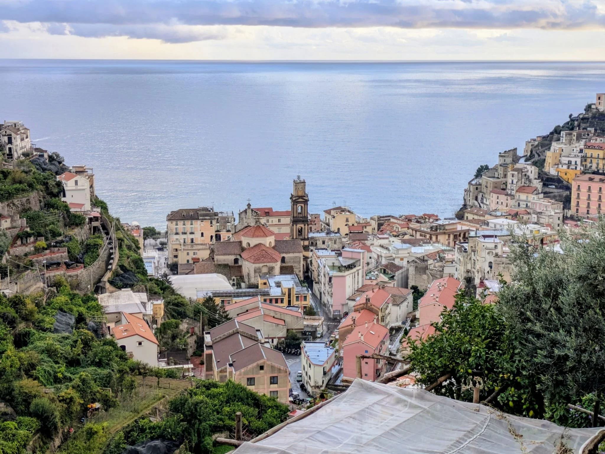 Minori on the Amalfi Coast with colorful buildings on hillsides overlooking the sea, with a cloudy sky above.