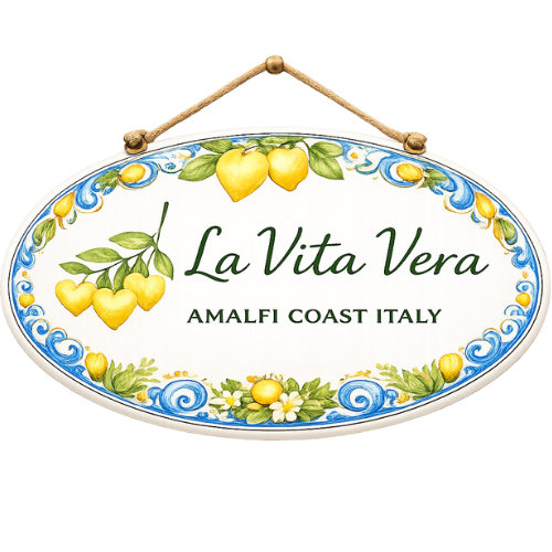 Decorative oval sign with yellow lemons and green leaves, reading "La Vita Vera, Amalfi Coast Italy."