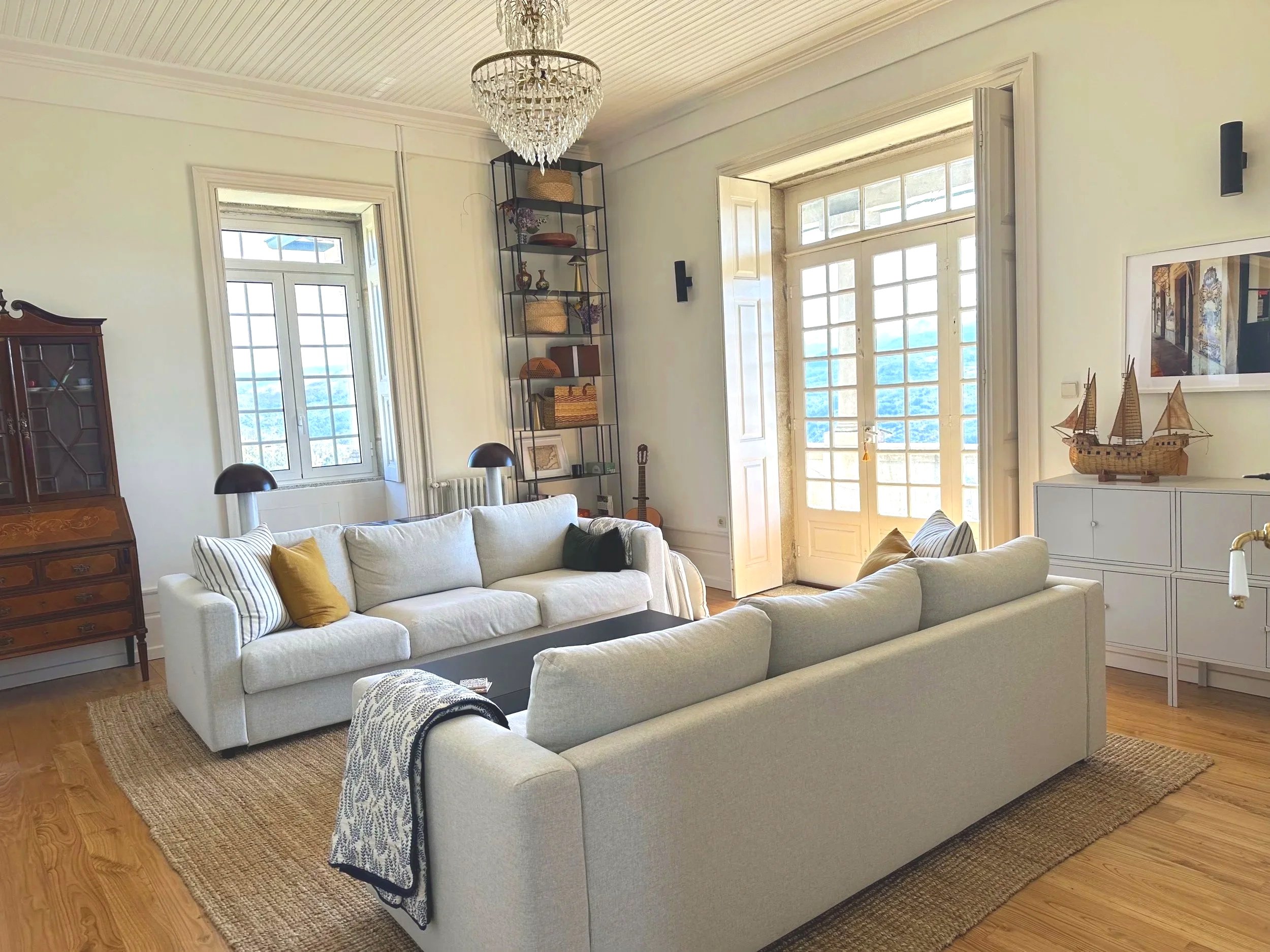 Middle-floor living room at Casa Belo Horizonte with two sofas, comfortable seating and natural light, large doors going out to terrace.