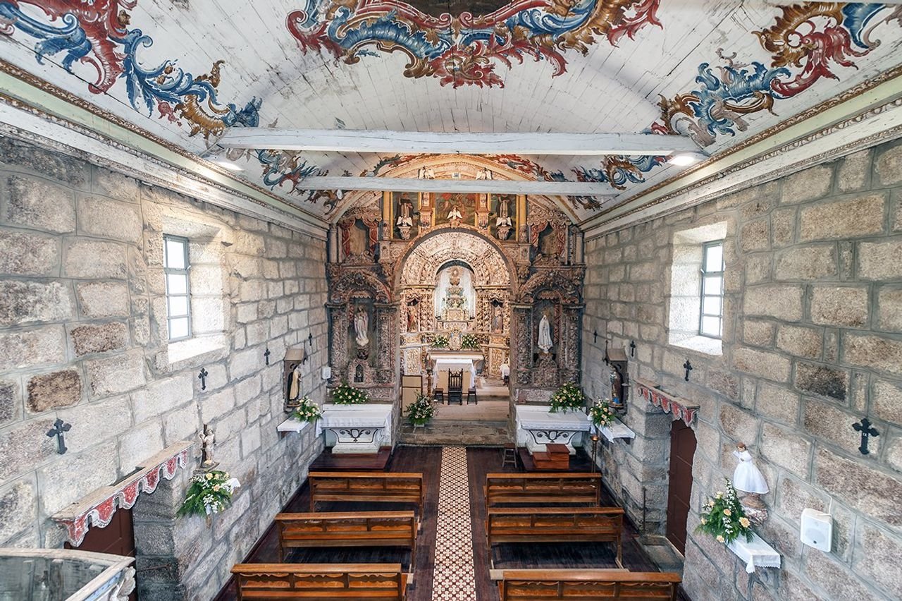 Interior of a Romanesque stone church on the Rota do Românico, featuring wooden pews and an ornate altar.
