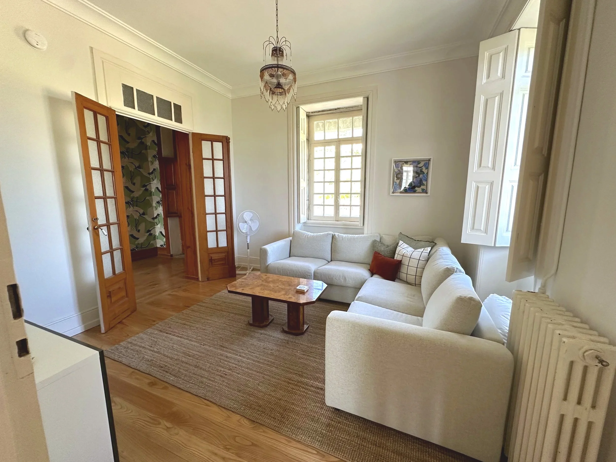 TV room and den at Casa Belo Horizonte with comfortable seating, hardwood floors, and natural light from open shutters.