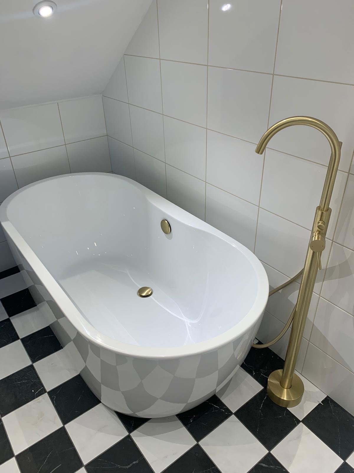 White freestanding bathtub with gold fixtures and a black-and-white checkered tile floor in a modern bathroom.