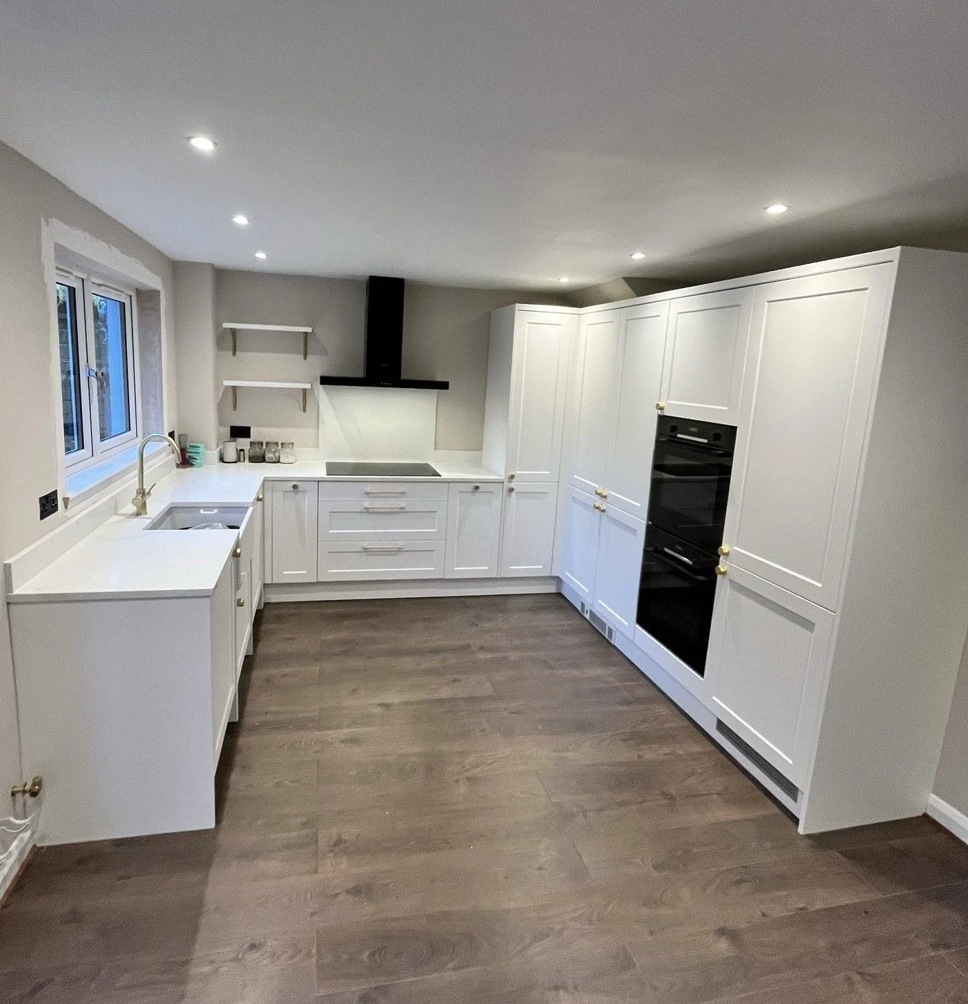 Modern kitchen with white cabinets, black oven, and wood flooring.