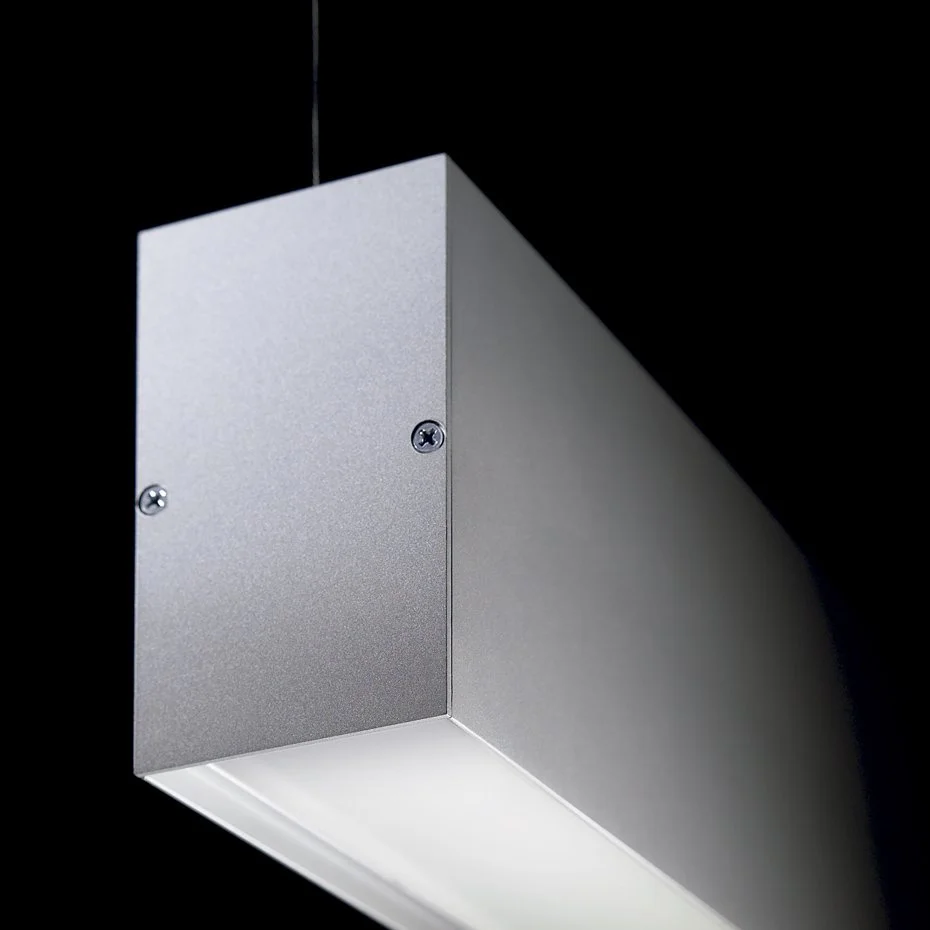 Luminária de teto prateada com luz branca, em ambiente escuro.