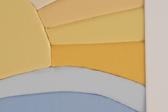 Close-up of a fabric art piece with yellow, orange, green, and blue fabric sections.