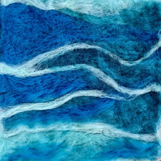 Close-up of textured fabric in shades of blue with white wavy lines.