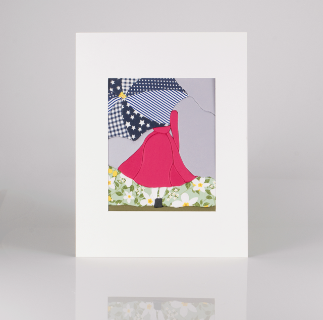 A fabric collage artwork of a lady holding a yellow umbrella, standing on a grassy patch with white flowers, with a cloudy sky background.