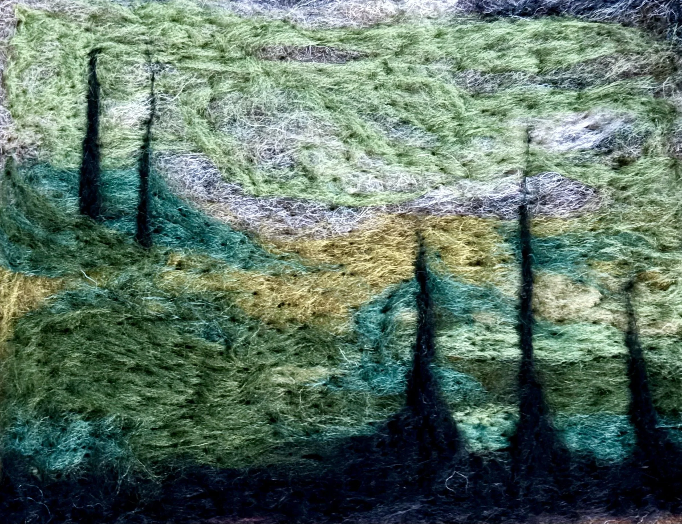 Abstract felted painting of a forest with green, yellow, and brown hues, featuring tall black trees.