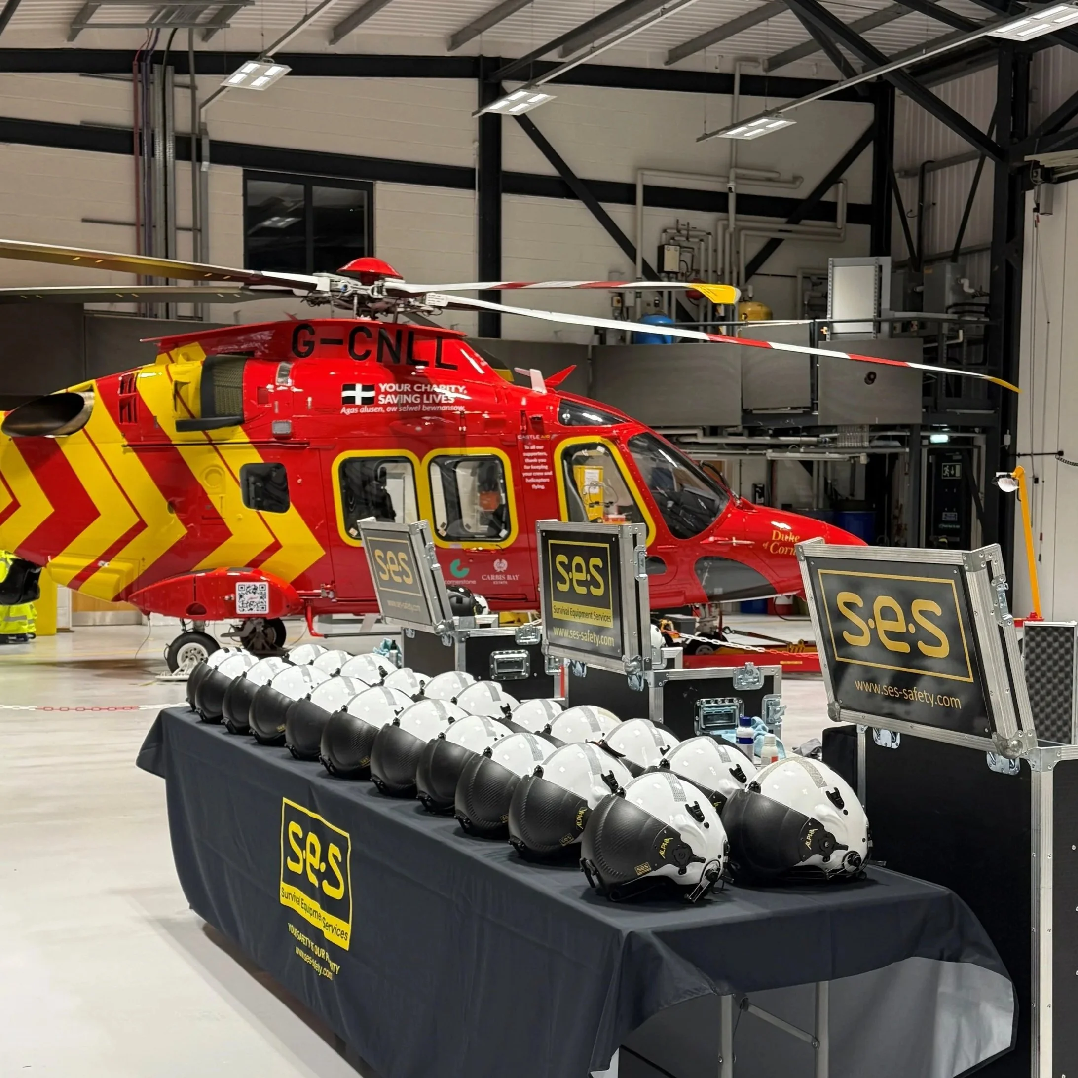 Emergency rescue helicopter inside a hangar with safety equipment and helmets on a table in the foreground.