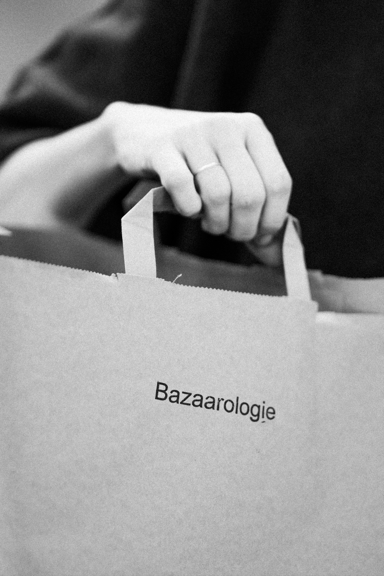 Une main qui déplace un bulletin de vote dans une urne, avec le mot "Bazaarsologie" sur la face visible de l'urne.