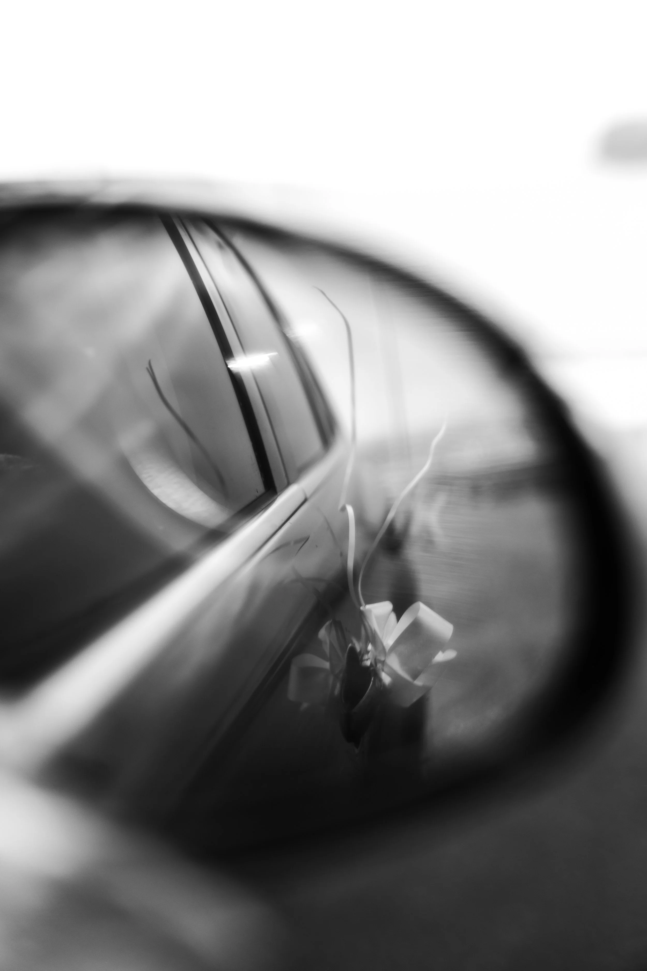 Photo en noir et blanc d'une voiture vue de côté, avec la lunette arrière en évidence.