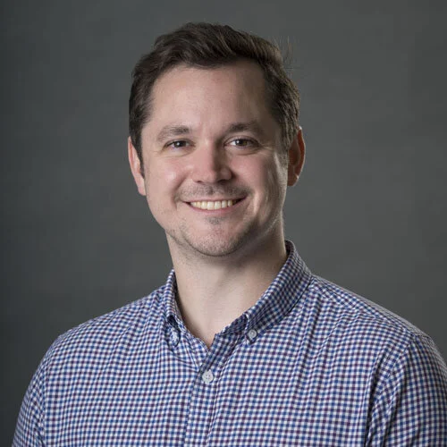 Smiling man in checkered shirt, gray background