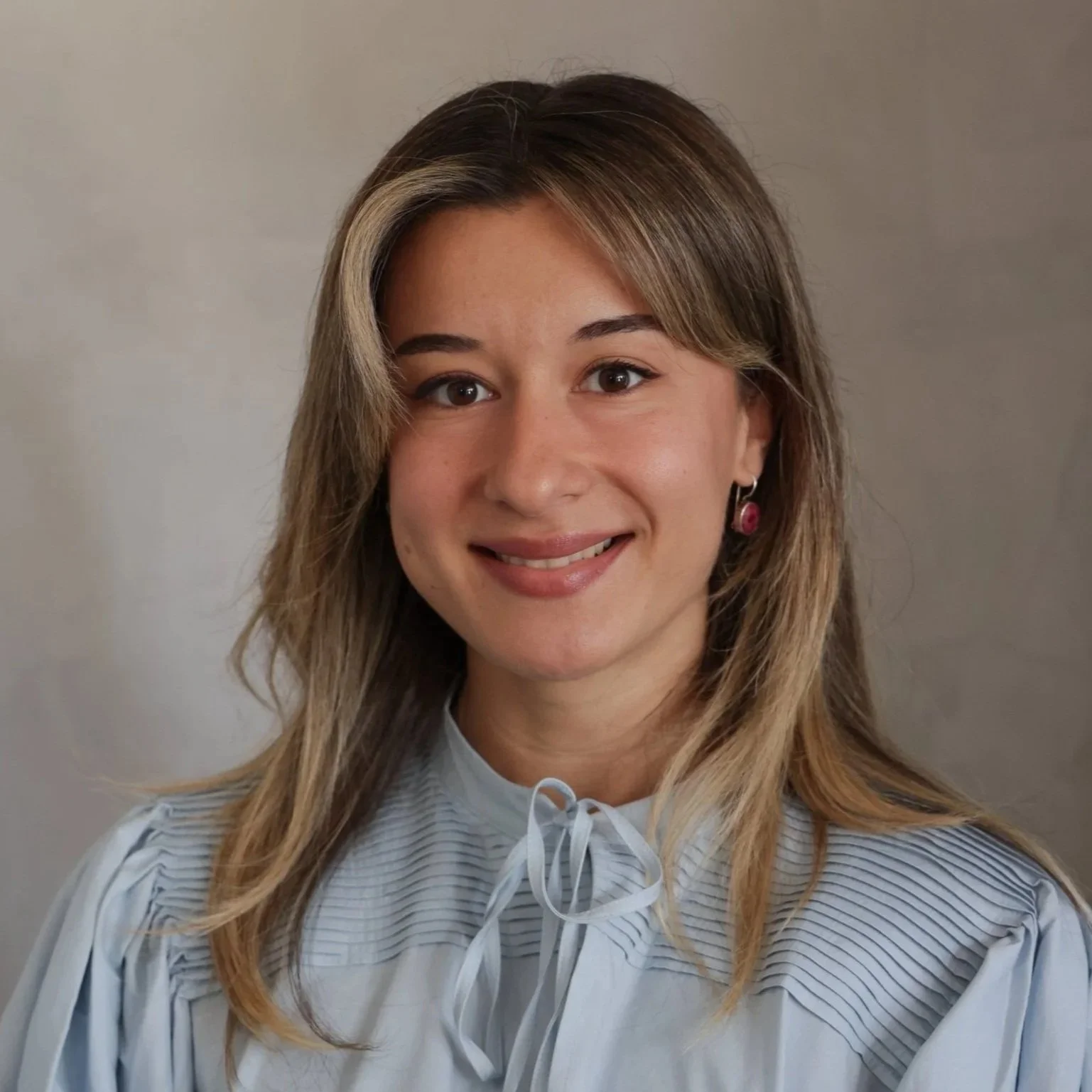 Young woman wearing a light blue blouse, smiling, with medium-length hair.