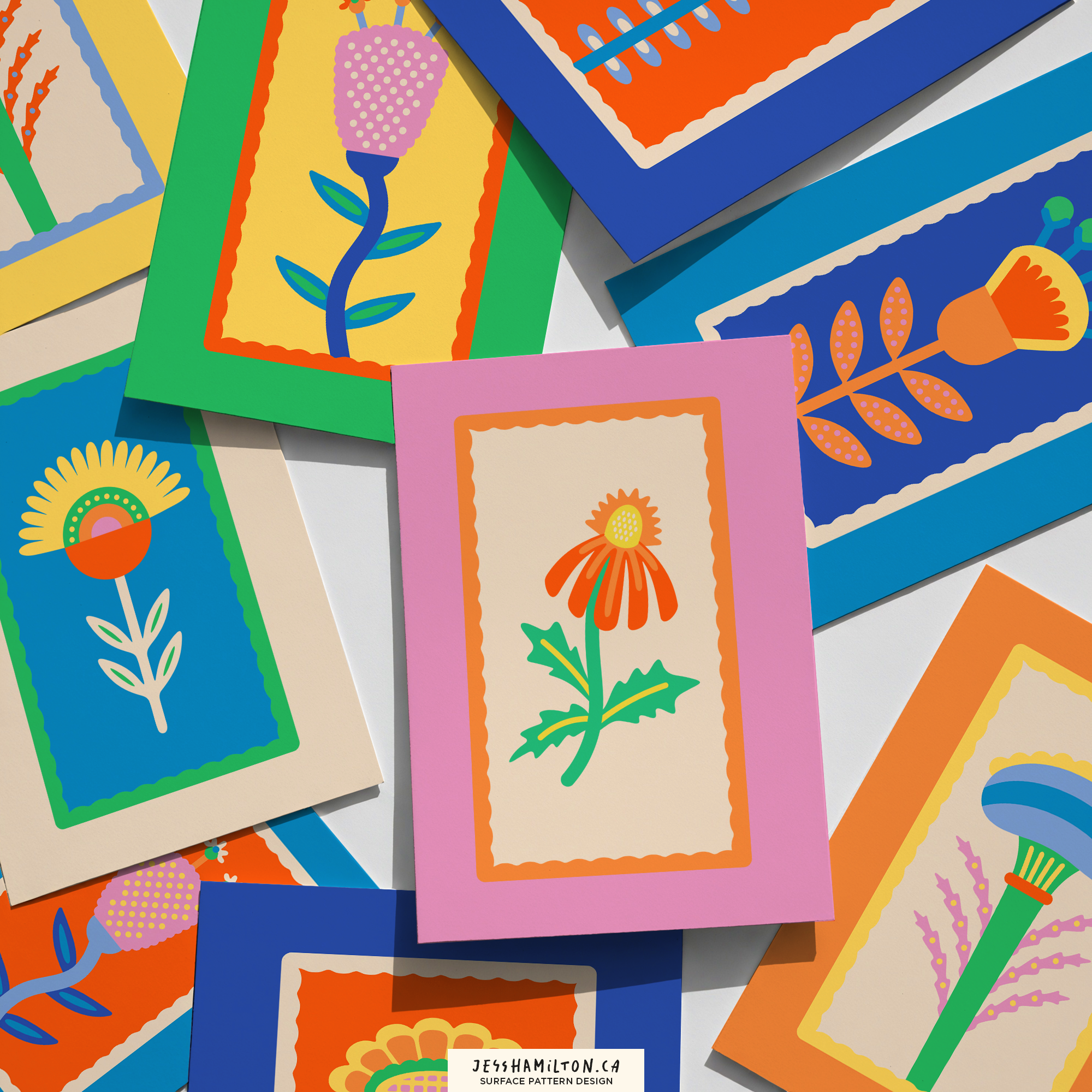 Colorful paper greeting cards with floral designs in bright colors, featuring stylized flowers and leaves with decorative borders, scattered across a white surface.