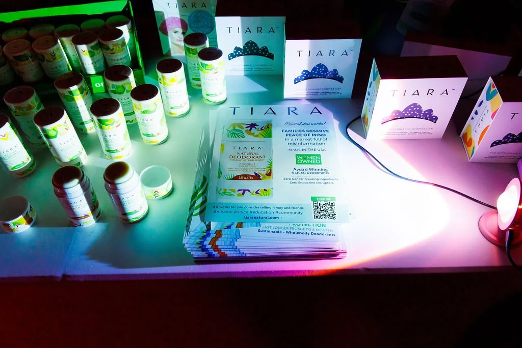 Display of Tiara natural deodorants and shower caps, with informational brochure and colorful lighting.