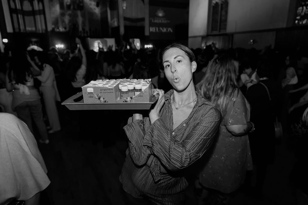 An image of a woman holding a tray of small energy drink bottles
