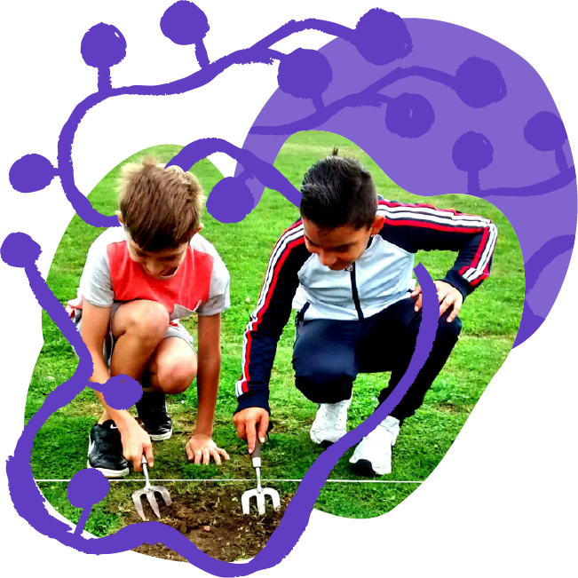 Two boys crouching on grass, planting or examining something in the soil with small garden tools, overlaid by a purple illustrative drawing of a microorganism.