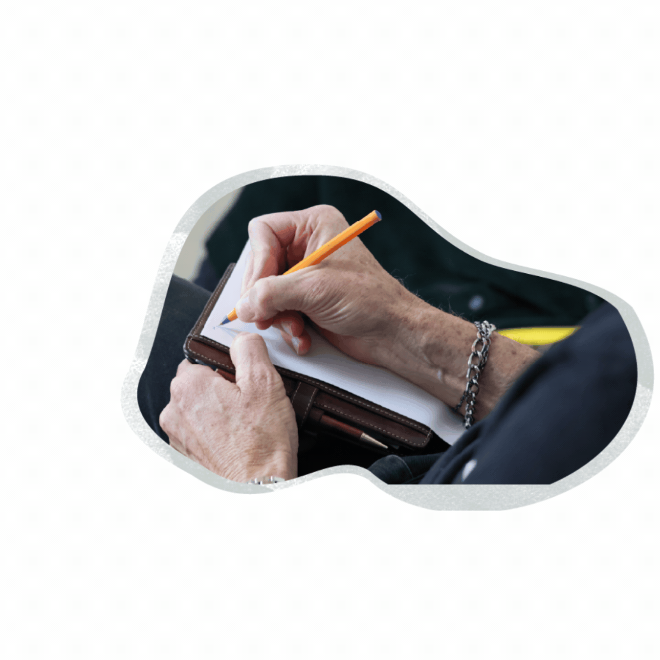 Close-up of an elderly person's hands writing on a notepad with a yellow pencil, wearing a silver bracelet, with a brown wallet underneath the notepad.