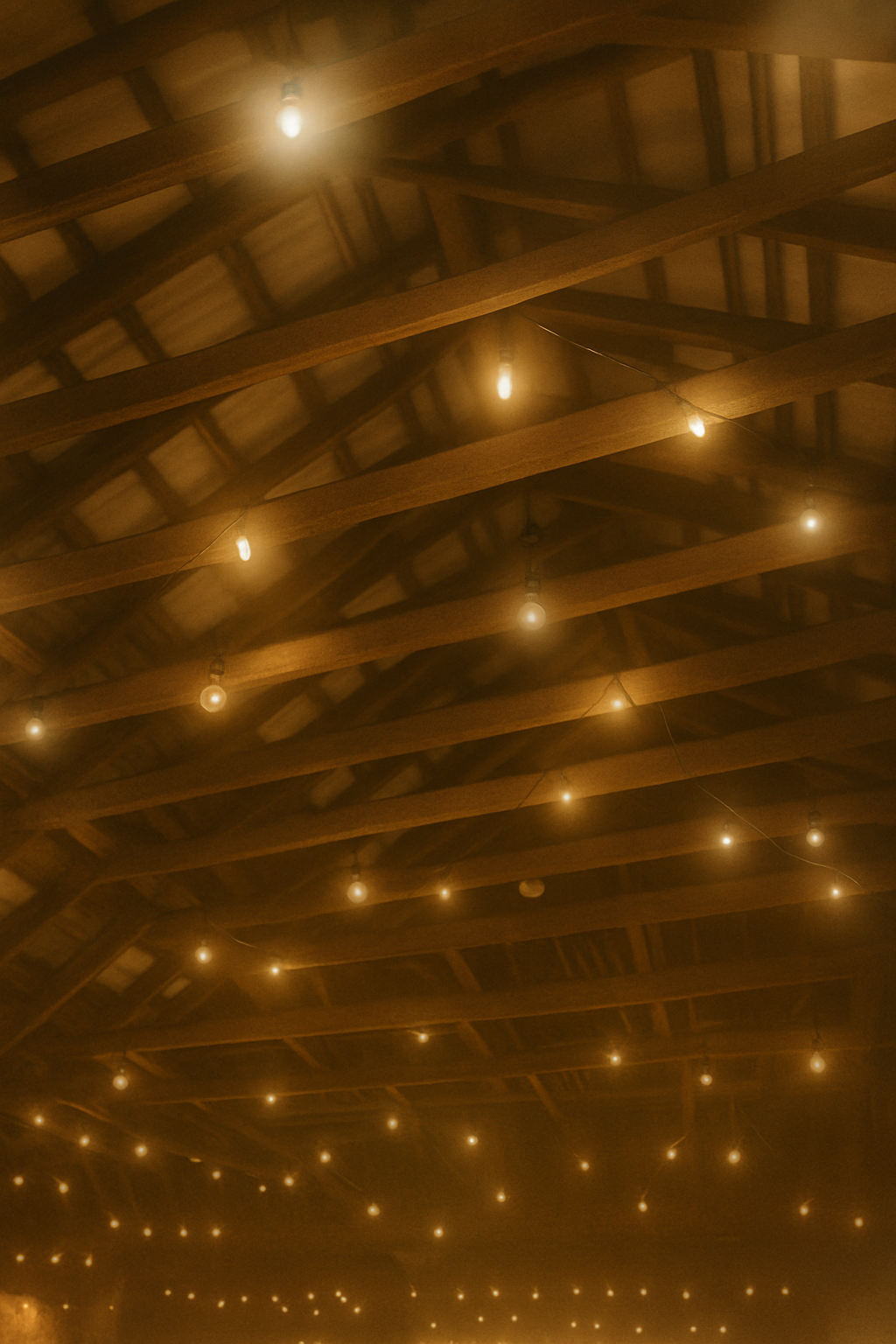 String of small warm white fairy lights hanging from the wooden ceiling beams of a rustic indoor space.