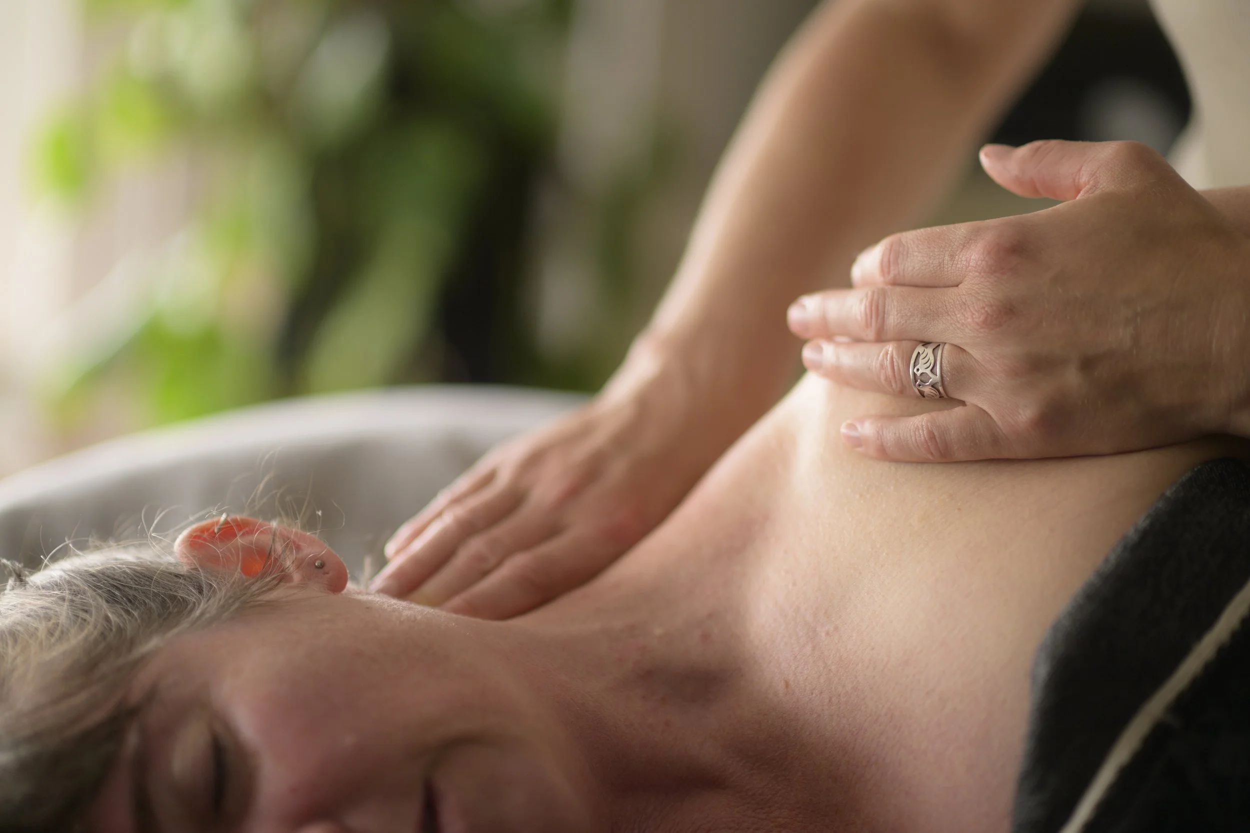 A person receiving a massage on their upper chest and shoulder area in a relaxed setting.