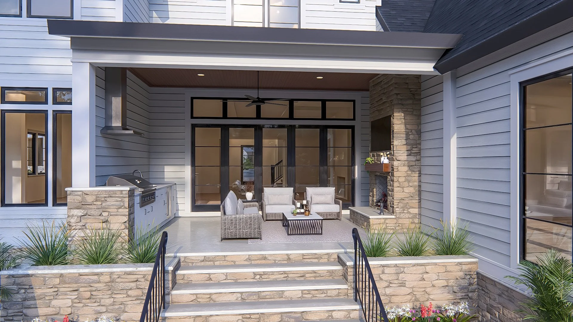 Outdoor patio with beige outdoor furniture, a built-in grill, and a stone fireplace, with stairs leading up to it and lush plants in the foreground.