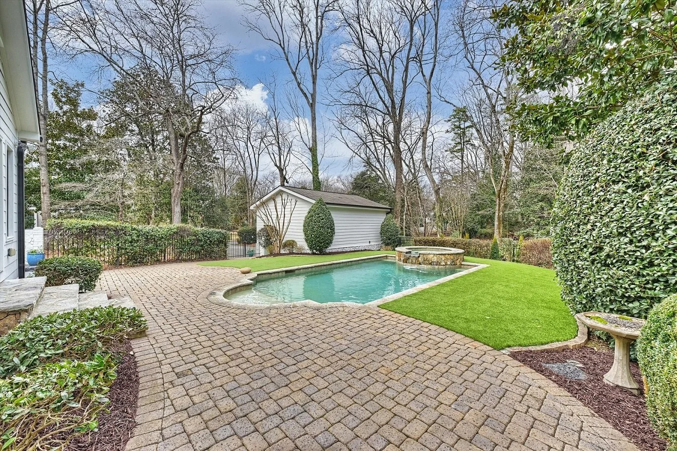 Private backyard with saltwater pool and raised spa, paver patio, turf lawn, and mature landscaping