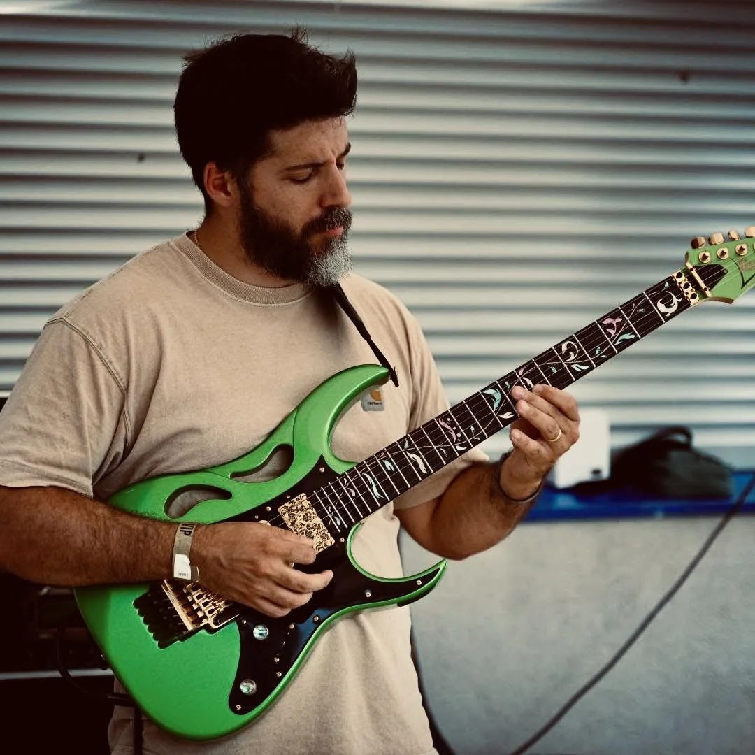 Homme jouant de la guitare électrique verte avec un fond de volets en métal.