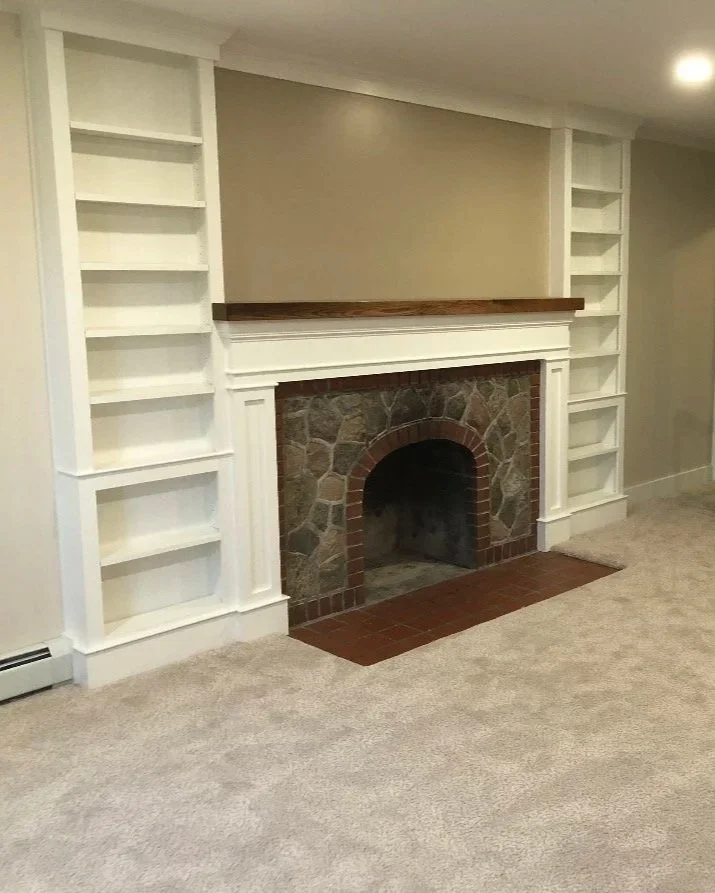 Rebuilt stone fireplace with custom white trim and built-in shelving.