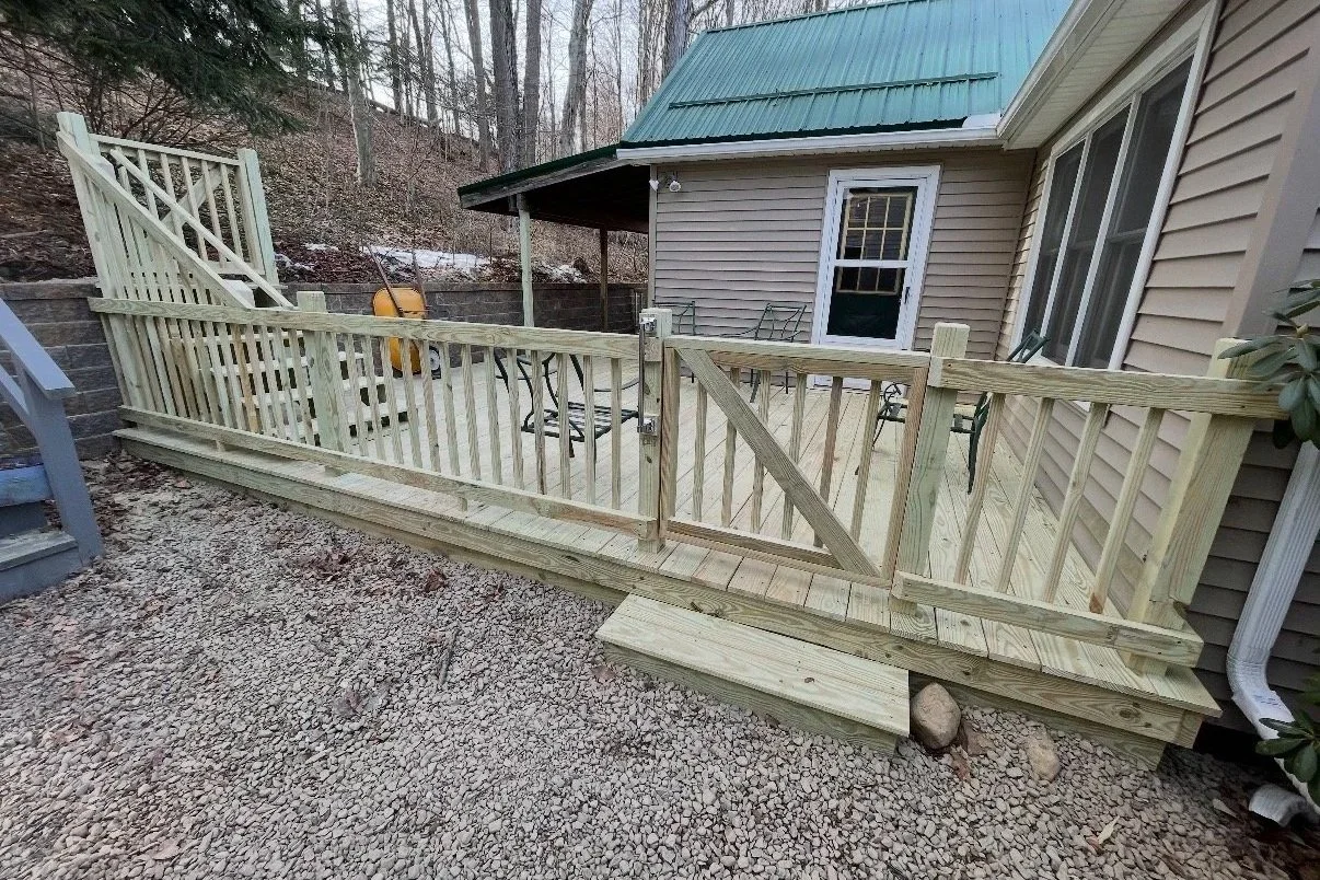 After: Newly constructed pressure-treated wood deck with railing, stairs, and patio furniture outside walk-out door.