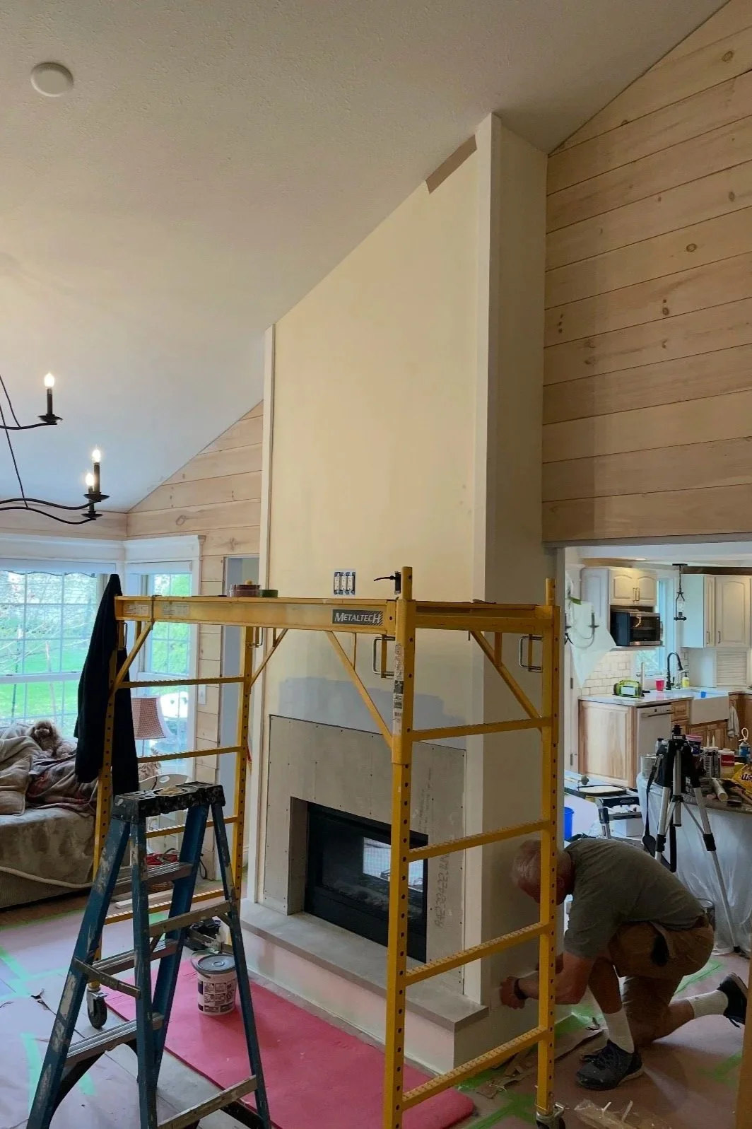 Before: Fireplace wall mid-construction with scaffolding and framing tools.