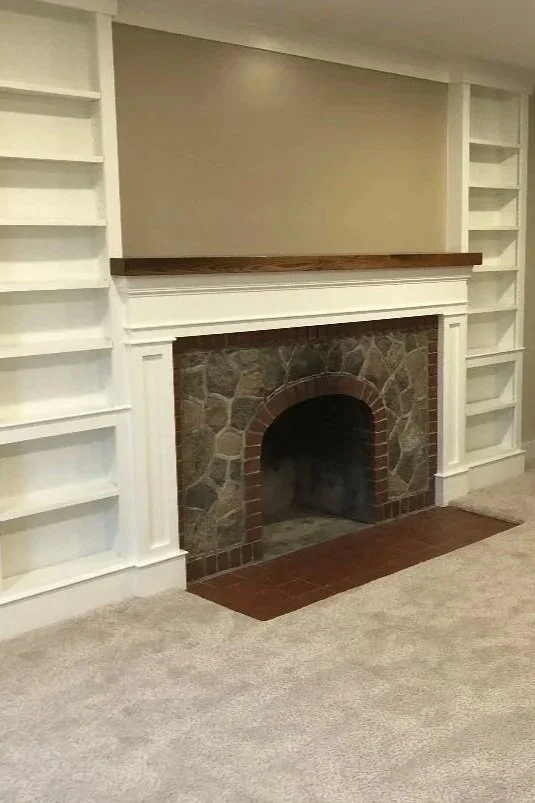 After: Rebuilt stone fireplace with custom white trim and built-in shelving.
