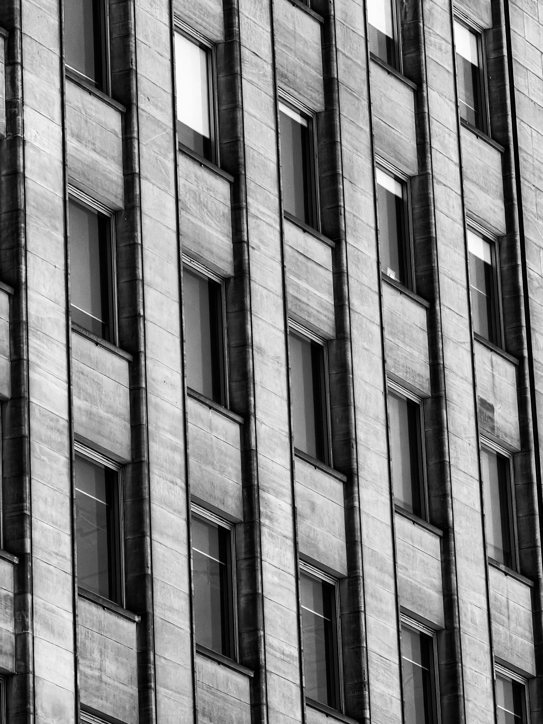 Vista de un edificio de varios pisos con ventanas rectangulares, fachada de piedra o concreto en tonos de gris.