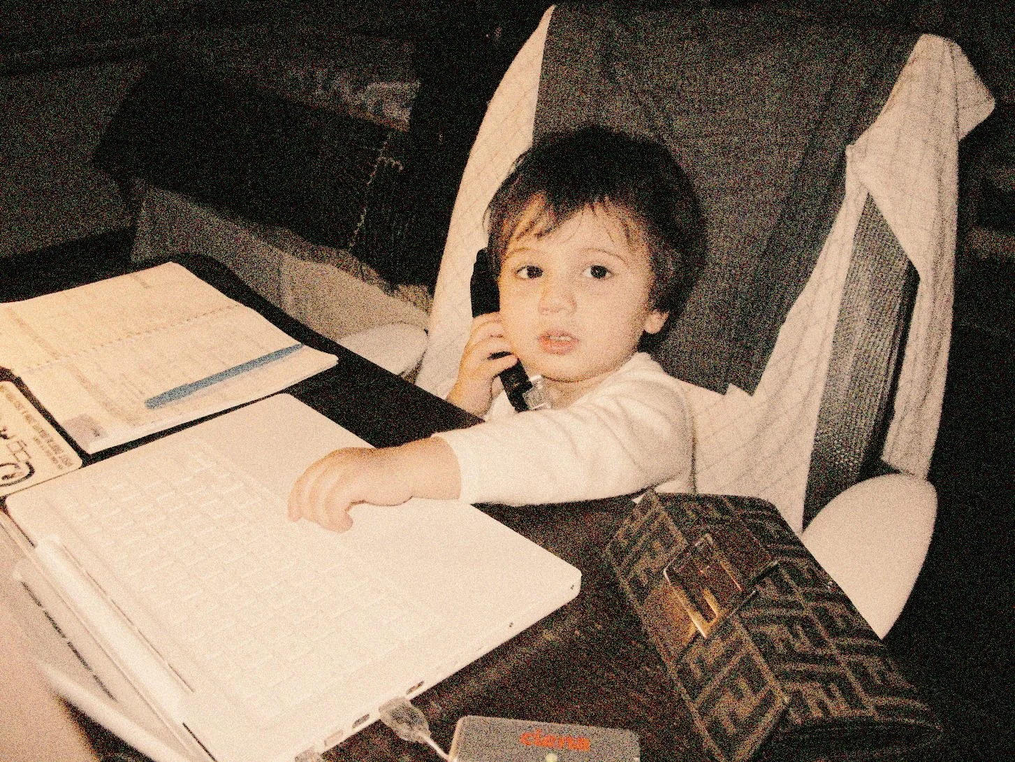 retro photo of baby on old school cell phone at a desk with fendi wallet in the foreground