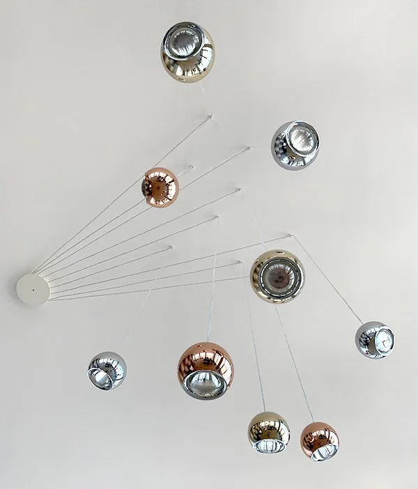Modern ceiling chandelier with multiple metallic and glass spherical light fixtures suspended by thin wires.