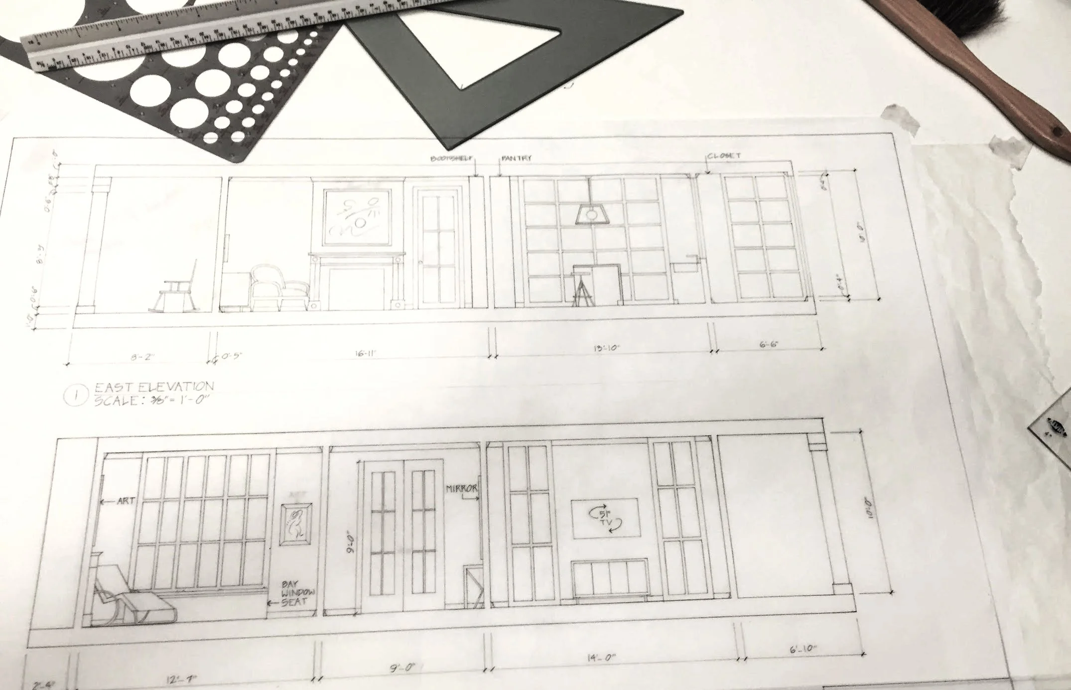 A detailed architectural blueprint of a building interior, including measurements, room labels, and furniture arrangements. There are drafting tools, such as a triangular scale, a protractor, and a ruler, placed on the blueprint.