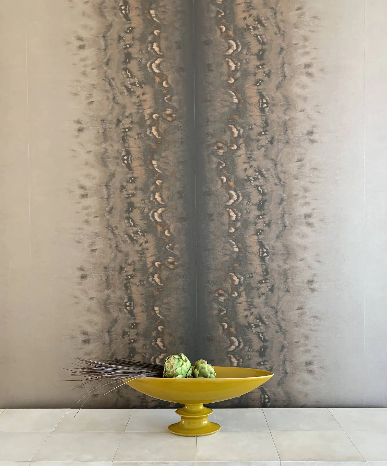 vignette: midcentury bowl holding artichokes in front of neutral abstract stripewallpaper