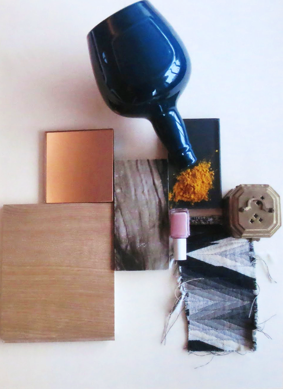 Arrangement of various objects including a large black hair dryer, a black framed photo with yellow flowers, a small pink candle, a beige decorative box, a weathered religious image, a piece of black and white fabric, blush-colored square plates, and two wooden panels, all placed on a light-colored surface.