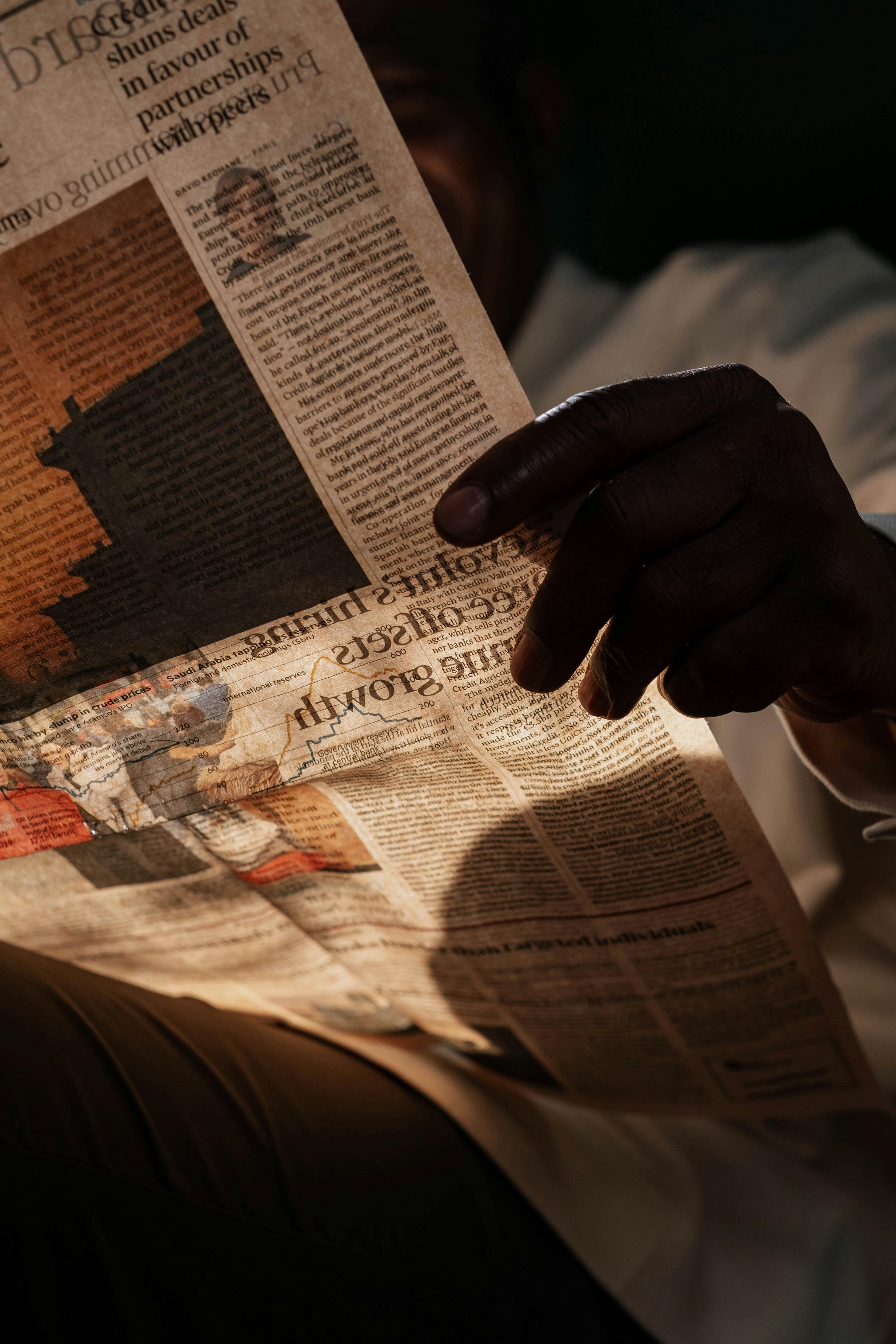 Une main sombre tenant un journal en lisant.